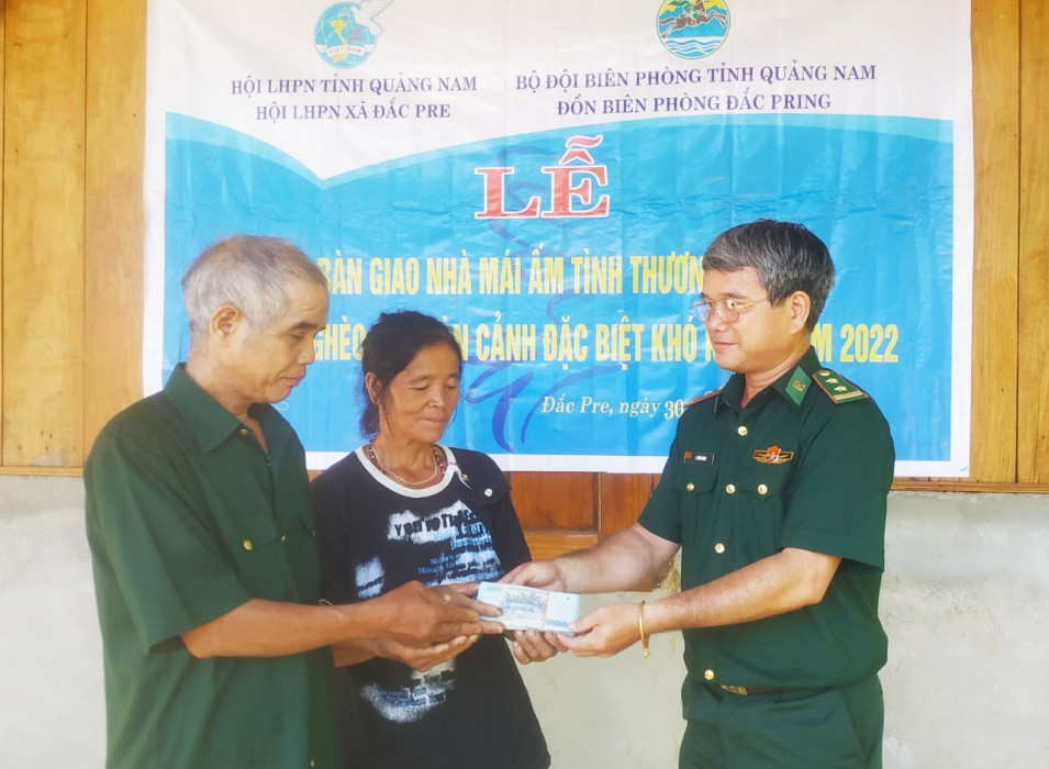 Đại diện Đồn Biên phòng Đắc Pring trao tiền hỗ trợ xây dựng nhà cho hộ gia đình bà Hiên Thị Hưm. Ảnh: VĂN VINH